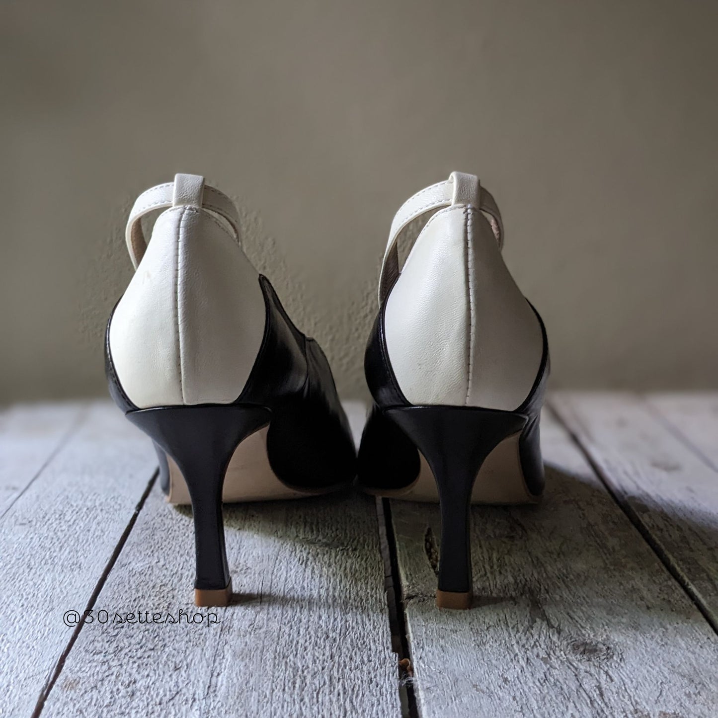 Décolleté con bordo sagomato a onde in pelle nera e tallone bianco con la punta aperta, sottile cinturino alla caviglia con tacco di 7 cm artigianale