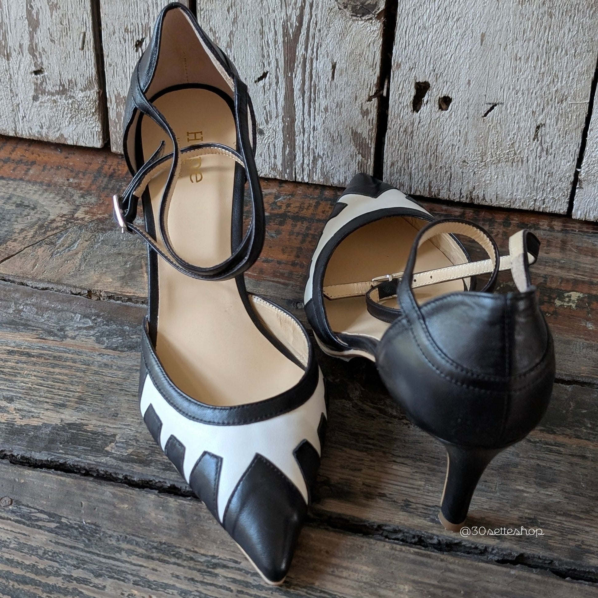Décolleté con tacco di media altezza realizzata in nappa nero con inserti geometrici in nappa panna con punta sfilata e cinturino alla caviglia.