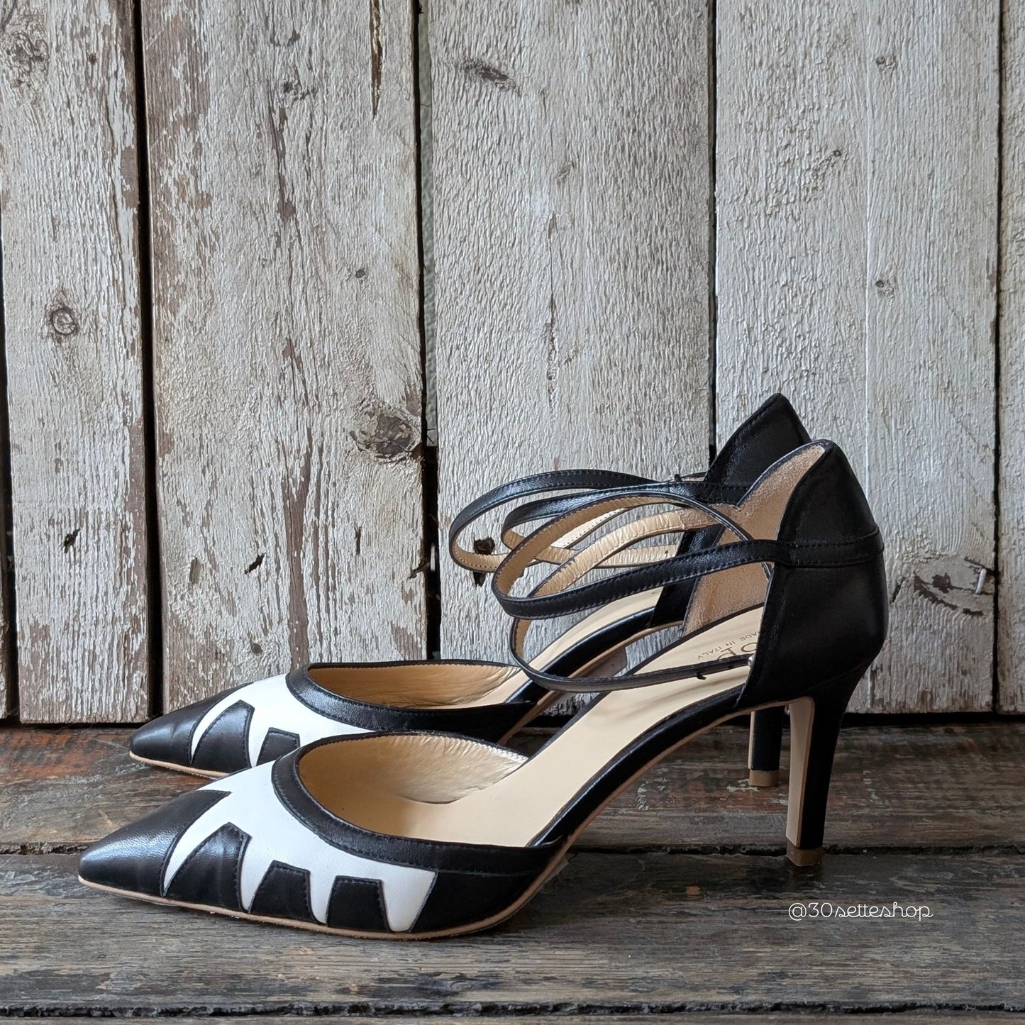 Décolleté con tacco di media altezza realizzata in nappa nero con inserti geometrici in nappa panna con punta sfilata e cinturino alla caviglia.