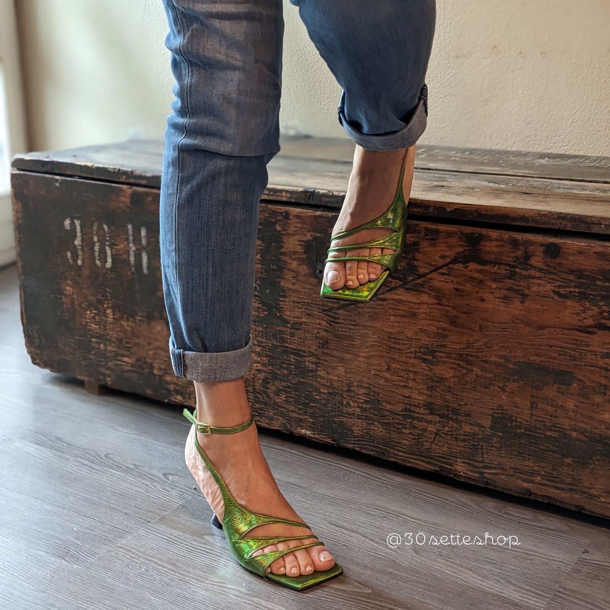 Sandalo Iris in nappa verde acido cangiante. Silhouette asimmetrica con dettagli originali cut-out di multi listini sottili.