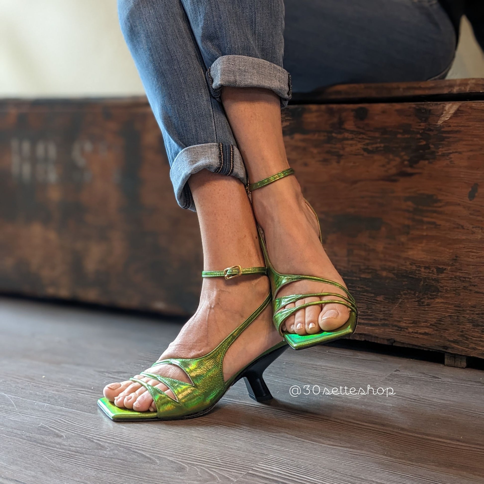 Sandalo Iris in nappa verde acido cangiante. Silhouette asimmetrica con dettagli originali cut-out di multi listini sottili.