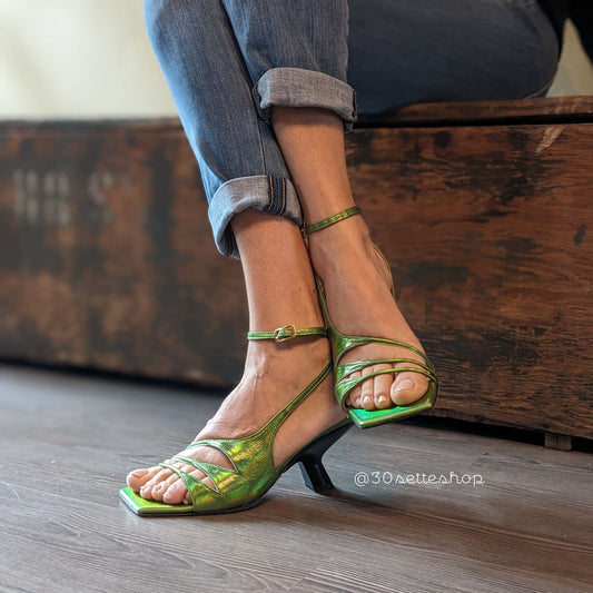 Sandalo Iris in nappa verde acido cangiante. Silhouette asimmetrica con dettagli originali cut-out di multi listini sottili.