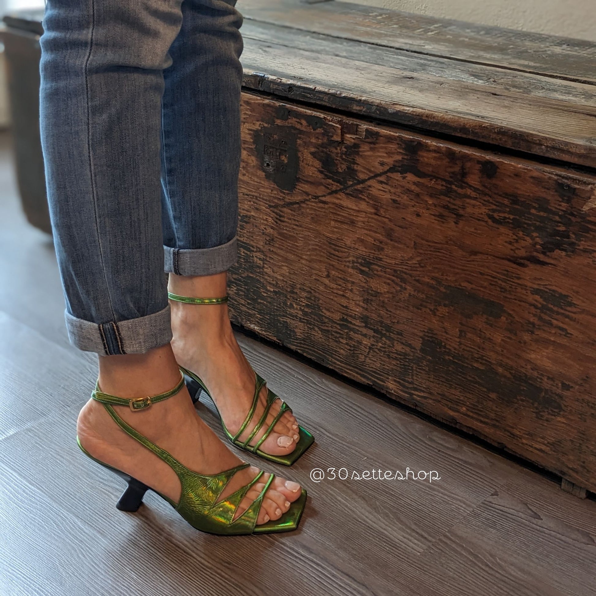 Sandalo Iris in nappa verde acido cangiante. Silhouette asimmetrica con dettagli originali cut-out di multi listini sottili.