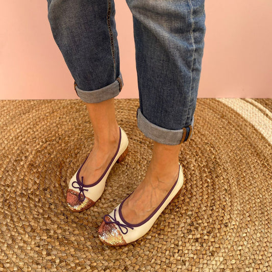 BALLERINE CON TACCO A PUNTA TONDA IN NAPPA PANNA E PUNTA A CONTRASTO IN GLITTER CIPRIA. IL FIOCCHETTO IN PUNTA E IL PROFILO IN TESSUTO INTORNO A TUTTA LA TOMAIA SONO VIOLA. MORBIDE E MOLTO COMODE GRAZIE ALLA FLESSIBILE SUOLA IN GOMMA, SOTTOPIEDE E FODERA IN PELLE.  TACCO LARGO RICOPERTO IN GLITTER DI 3 CM. CALZATA REGOLARE. CALZATA REGOLARE. TOMAIA - FODERA - SOTTOPIEDE IN PELLE 100%. PRODOTTO IN ITALIA, MARCHE DA LE TRALLERINE.