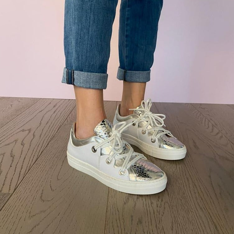 SNEAKERS ALLACCIATA IN MORBIDA NAPPA BIANCA CON BORDATURA E LINGUETTA IN NAPPA ARGENTO LAMINATO A SPECCHIO CON STAMPA PITONE. PASSALACCI IN METALLO ARGENTO SATINATO. FONDO A CASSETTA IN GOMMA COLOR CIPRIA LEGGERISSIMO. FUSSBETT ESTRAIBILE RICOPERTO IN PELLE CON RIALZO INTERNO SUL TALLONE DI 1,5 CM. CALZATA COMODA. SE HAI DUBBI, CONTATTACI VIA SMS O WHATSAPP AL 351/8950405 TI CONSIGLIEREMO NELLA SCELTA. TOMAIA - FODERA - SOTTOPIEDE IN PELLE 100%. PELLAMI ITALIANI DI QUALITÀ. PRODOTTO IN ITALIA, MARCHE