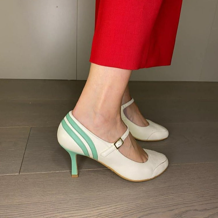 DÉCOLLETÉ BICOLORE IN MORBIDA NAPPA PANNA E DECORAZIONI IN NAPPA ACQUA. PUNTA ROTONDA E UN SOTTILE CINTURINO ALLA CAVIGLIA, MOLTO BON TON, CHE ASSICURA LA SCARPA AL PIEDE NELLA CAMMINATA. CALZATA REGOLARE CHE ABBRACCIA BENE IL PIEDE. SOTTOPIEDE IMBOTTITO DI 3 MM E FODERA IN PELLE. TACCO 7 CM. TOMAIA - FODERA - SOTTOPIEDE IN PELLE 100%. PELLAMI ITALIANI DI QUALITÀ. FONDO CUOIO RIGENERATO. CINTURINO REGOLABILE CON FIBBIA. PRODOTTO IN ITALIA, MARCHE DA HOPE.