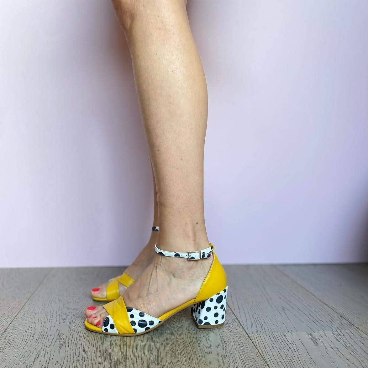 Sandalo in pelle bicolore giallo senape abbinata a una stampa dalmata in bianco e nero con tacco medio di 5 cm e cinturino alla caviglia.